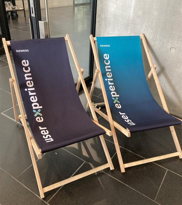 Picture of two blue lounge chairs at the UX camp Berlin, which say "user experience" on them.