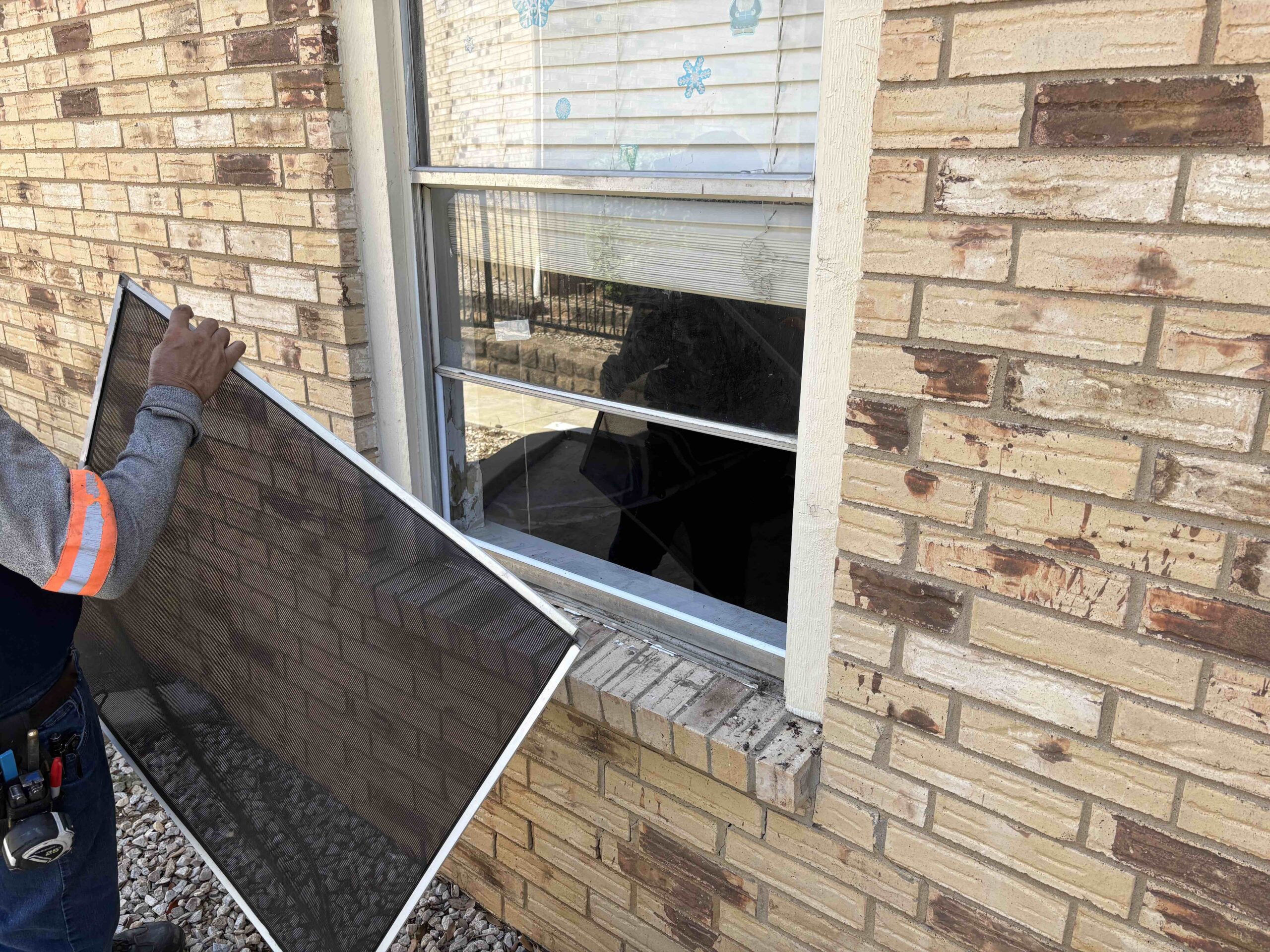 Picture from field service management software research of a field tech installing a window screen.