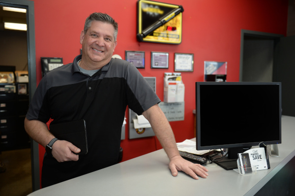 owner of automotive repair shop Steve, standing at customer service counter