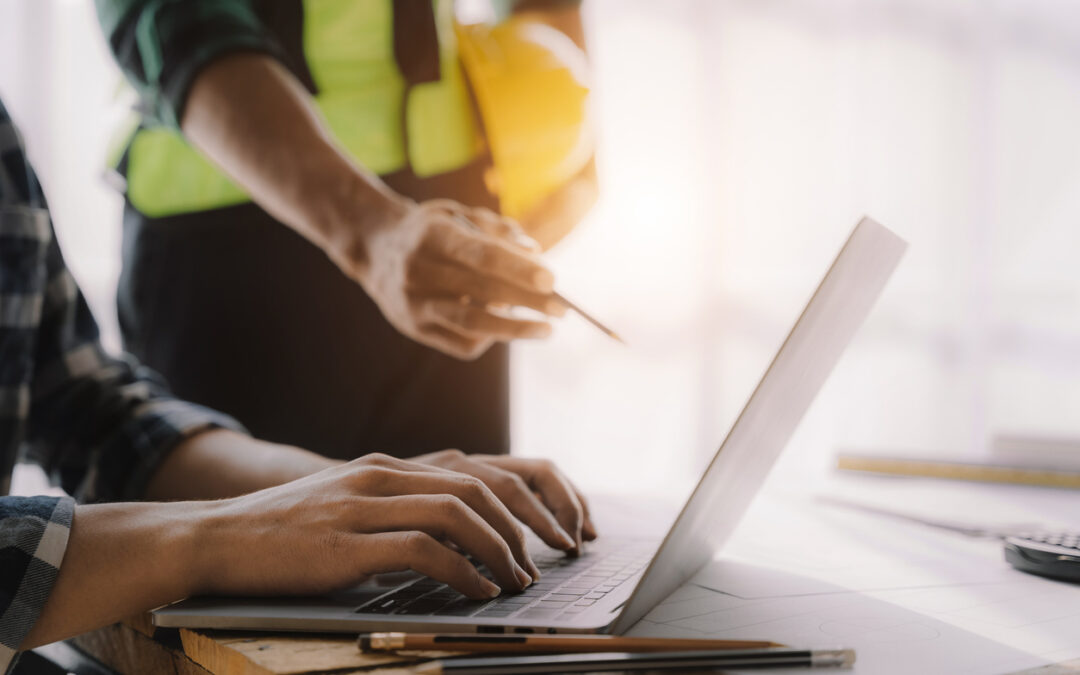 A construction manager is looking at their KPI tracking on their laptop to improve the construction company's success