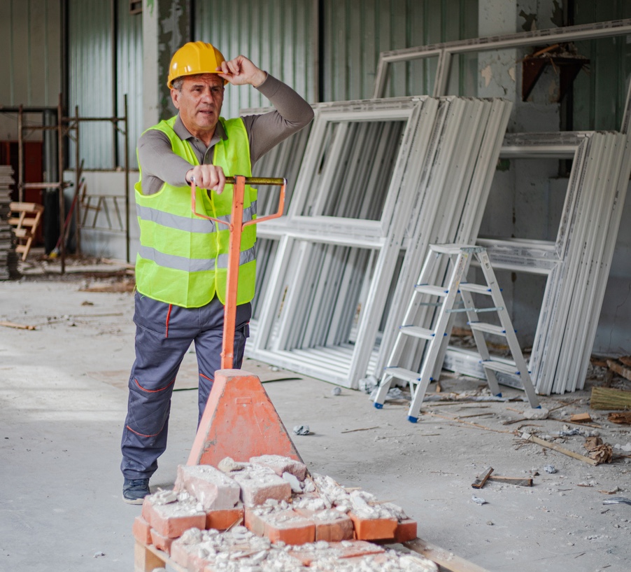 a construction man pushing a cart with very few bricks on it