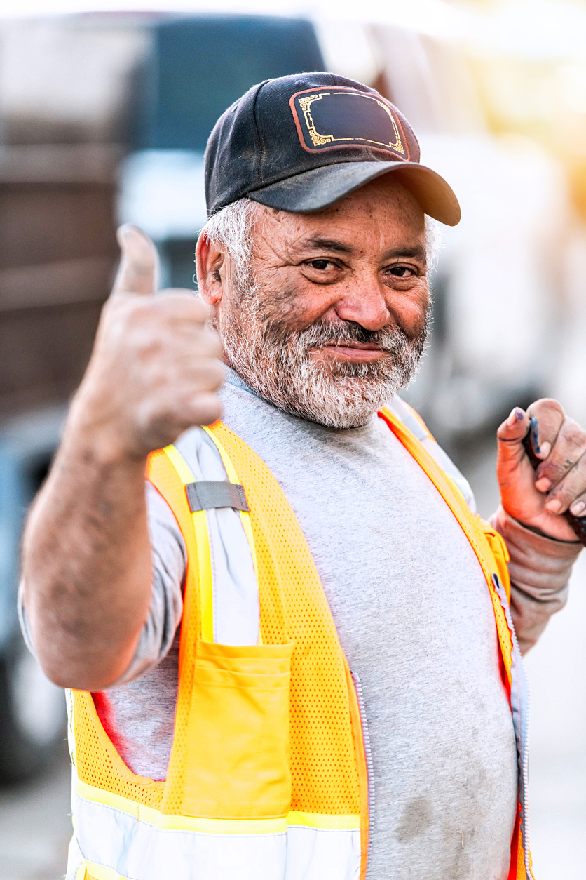 An older construction manager puts a thumbs-up 